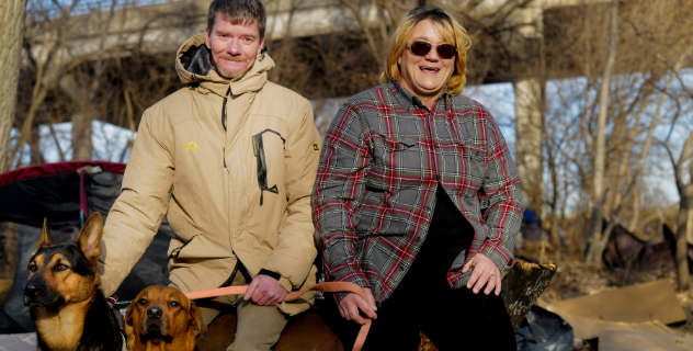 Jeff and Brandi, a couple who found happiness with Joppa's help. They're pictured sitting and smiling with their two large dogs.